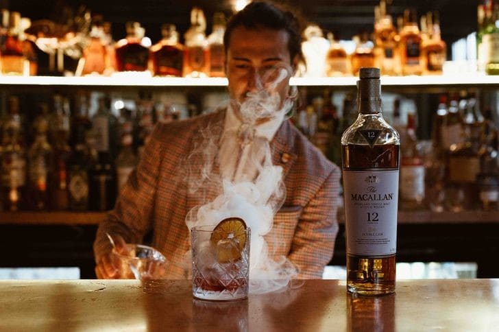 Bartender che prepara un cocktail affumicato al bancone