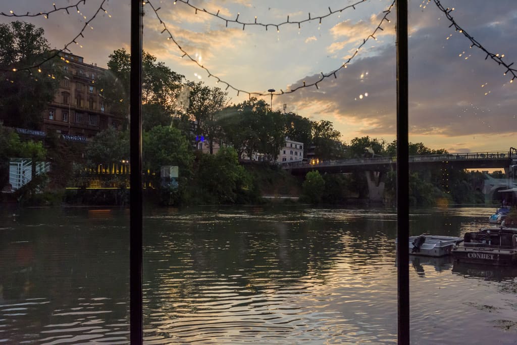 Il Tevere al tramonto visto dalle vetrate, con le luci e il ponte