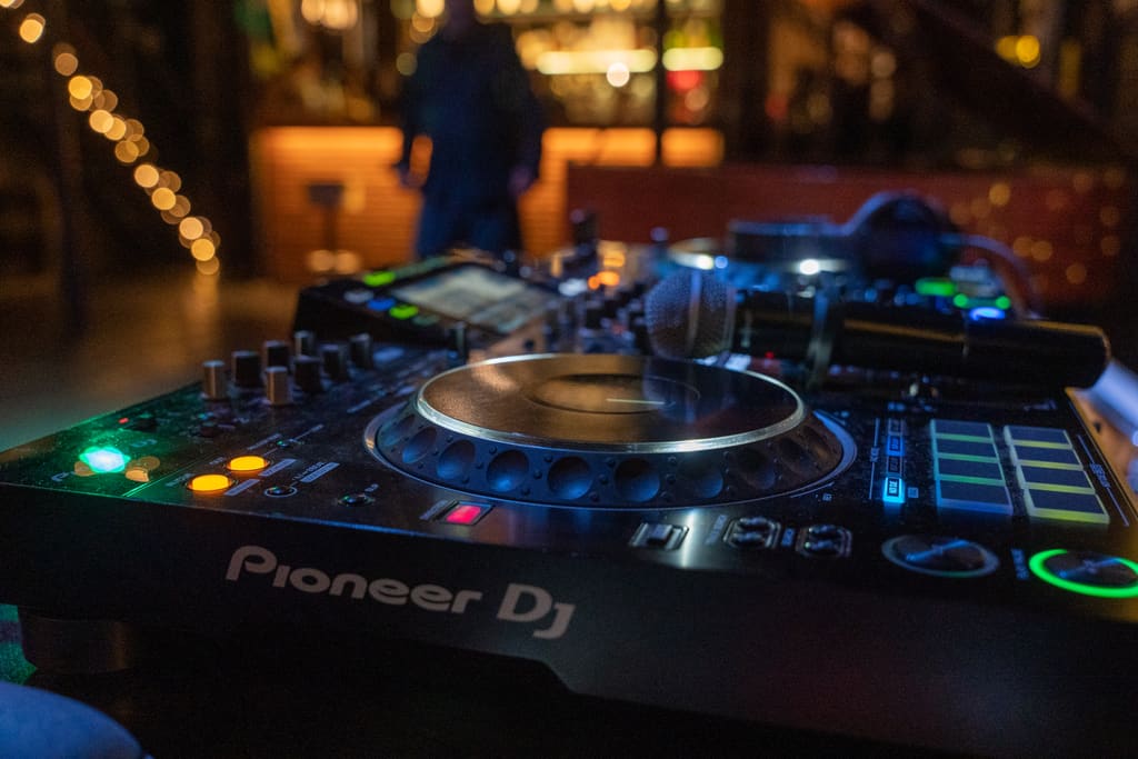 Console DJ pronta per la serata, con le luci del bar sullo sfondo