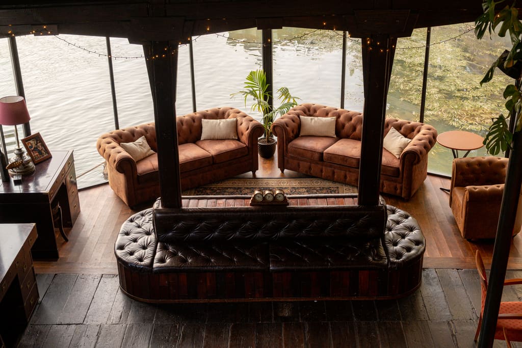 Salotto con divani chesterfield davanti alle vetrate affacciate sul Tevere